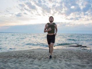A man running with a weight vest on the beach