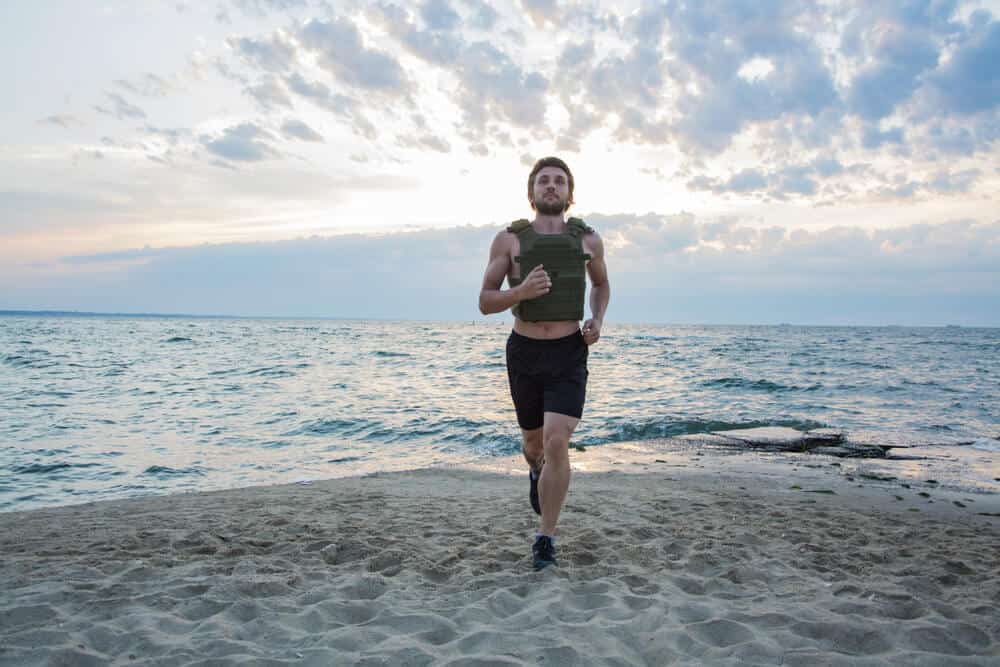 A man running with a weight vest on the beach