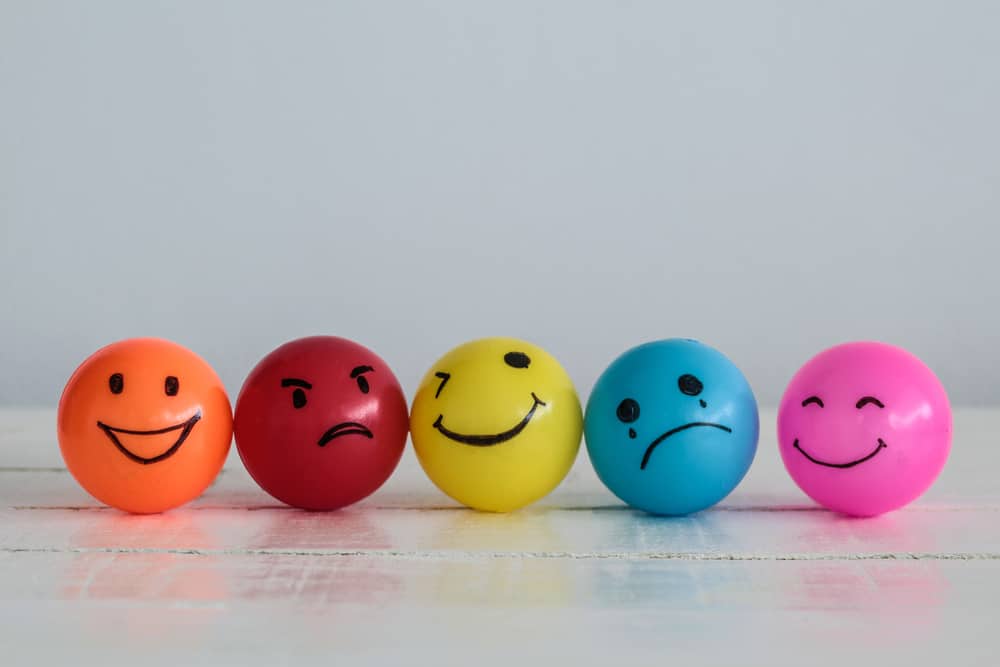 Four ping pong balls in different colors wearing different emotions.